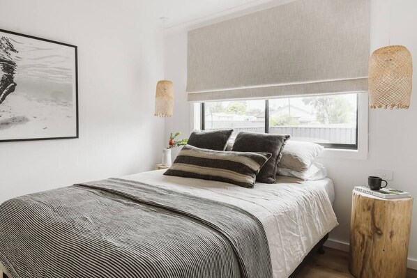 A bedroom with a bed, a window, a wall-mounted artwork, and a bedside table with a cup. - The Lull Culburra (Culburra Beach)