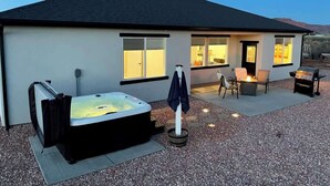 Una casa moderna con jacuzzi, mobiliario exterior y zona de barbacoa.