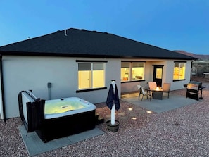 A modern house with a hot tub, outdoor seating, and a barbecue area.