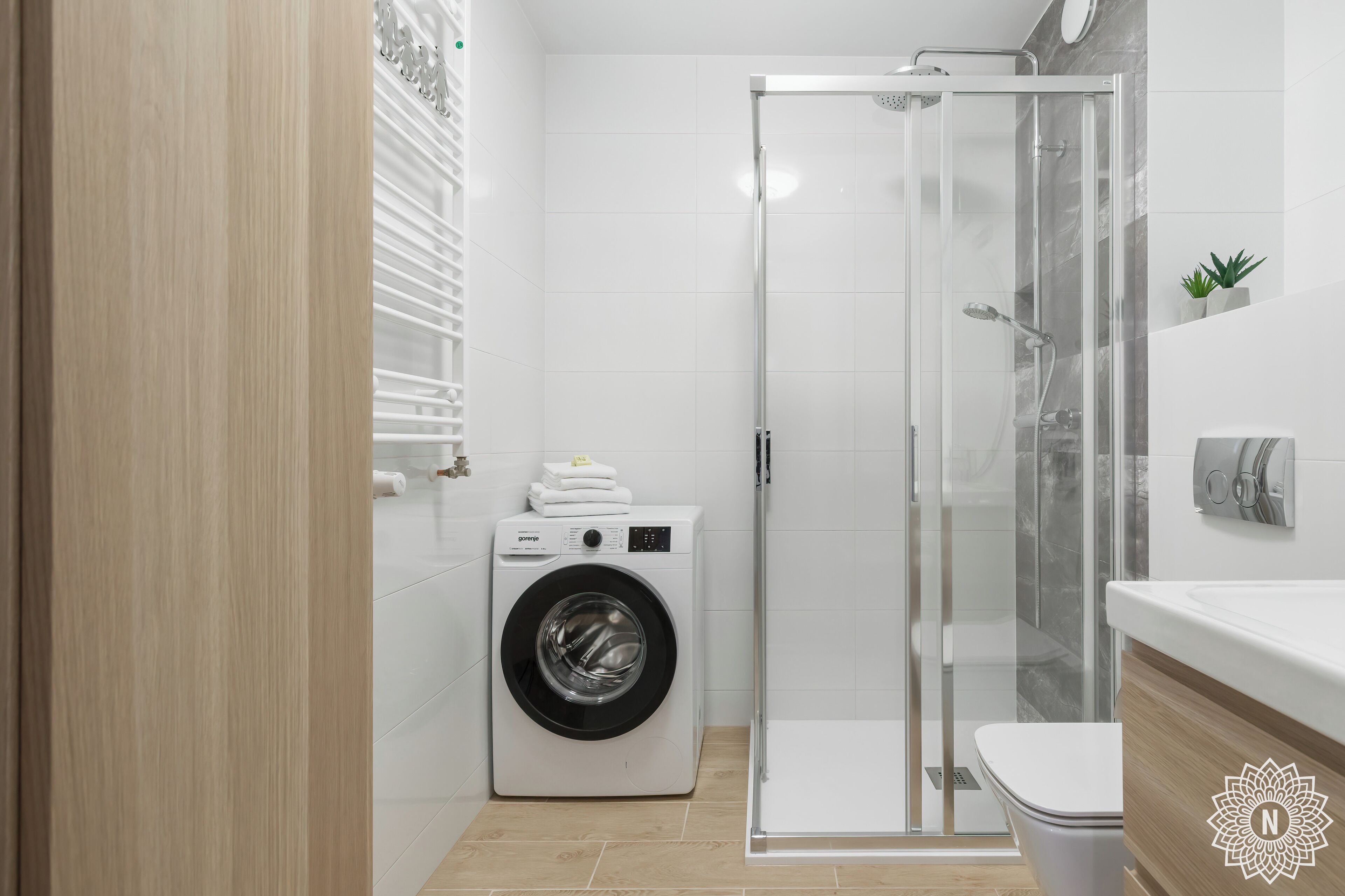 Een moderne badkamer met een wasmachine, een douchecabine van glas en een toilet.