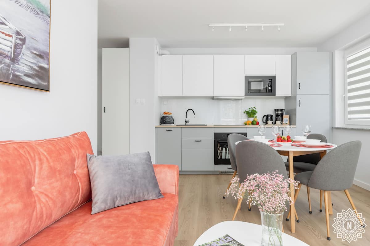 A modern kitchen with white cabinets, a microwave, and a dining area with a table and chairs.
