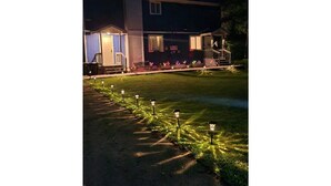 A building with a covered porch, a lawn with decorative lights, and a pathway. - Cozy Poconos Spa Retreat Near Hiking, Lakes & Fall Foliage (Tobyhanna)