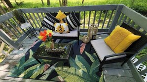 A wooden deck with a bench and a table, adorned with cushions and a vase of flowers. - Cozy Poconos Spa Retreat Near Hiking, Lakes & Fall Foliage (Tobyhanna)