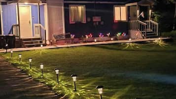 A building with a covered porch, a lawn with decorative lights, and a pathway.