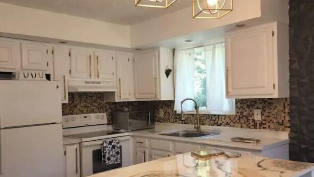 A modern kitchen with white cabinets, a marble island, and pendant lighting. - Cozy Poconos Spa Retreat Near Hiking, Lakes & Fall Foliage (Tobyhanna)