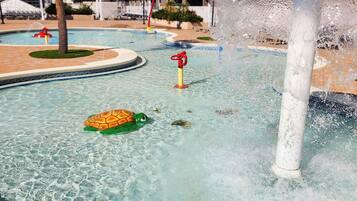 Zona de piscina con una fuente, un flotador con forma de tortuga y una palmera.