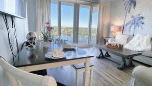 A spacious room with a dining area, a sofa, and a balcony with a view. - Private end unit, boasting incredible views for am incredible vacation! (Panama City Beach)