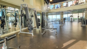 A spacious gym with various exercise equipment, a mezzanine level, and large windows. - Private end unit, boasting incredible views for am incredible vacation! (Panama City Beach)