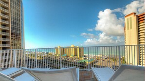 A balcony with white lounge chairs and a view of a cityscape and beach. - On the most private end of the building, accessible and gorgeous! (Panama City Beach)