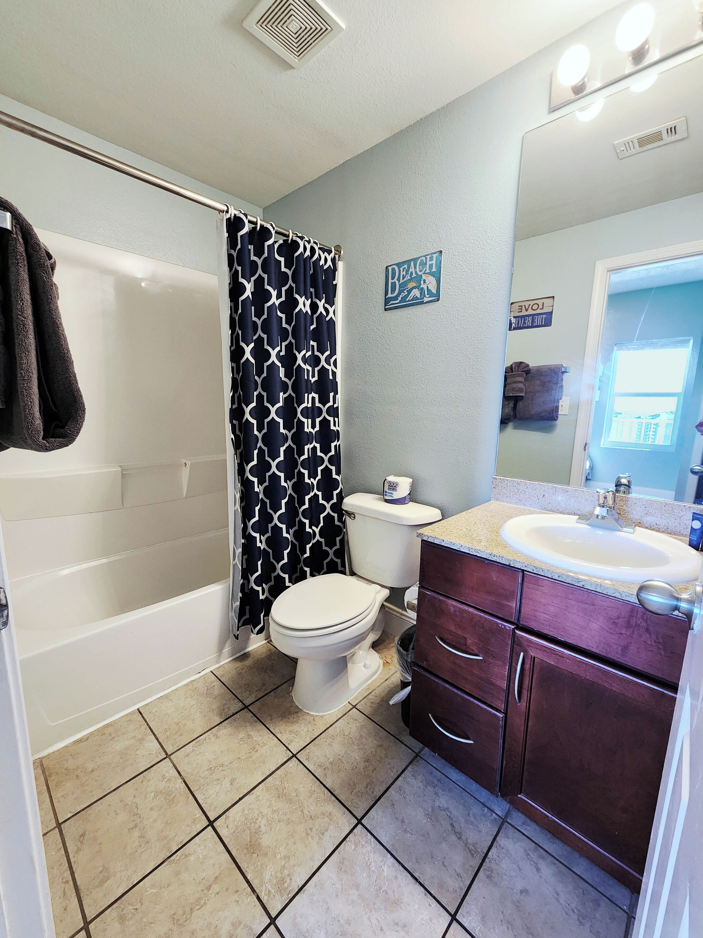 A bathroom with a bathtub, toilet, vanity with a sink, and a shower curtain.