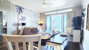 A dining area with a white chair, a black table, and a ceiling fan. - Exceptional unit! Extra large offering the best set up and views! (Panama City Beach)