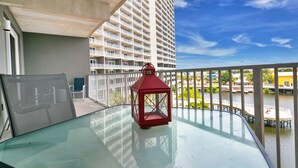 A balcony with a glass table, a red lantern, and a view of a high-rise building and water. - Best Location, 3rd floor condo! Enjoy the incredible views and privacy! (Panama City Beach)