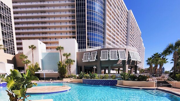 A hotel with a swimming pool, palm trees, and a modern building with balconies. - Best Location, 3rd floor condo! Enjoy the incredible views and privacy! (Panama City Beach)