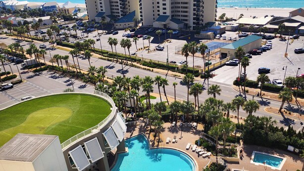 A resort with a large swimming pool, palm trees, and a view of the ocean.