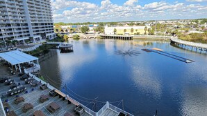 A waterfront deck with outdoor seating and a view of a large building across the water.