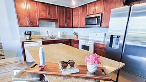 A modern kitchen with wooden cabinets, stainless steel appliances, and a granite countertop.