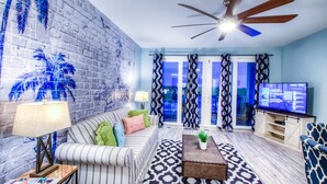 A living room with a sofa, coffee table, TV, and patterned rug. - Perfect views! Incredible experience! Best onsite restaurants and shops! (Panama City Beach)