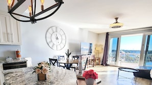 Uma cozinha ampla com uma ilha grande, sala de jantar com vista e sala de estar com varanda.