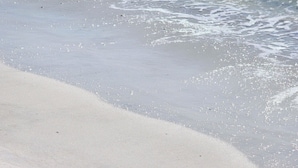 Uma praia com águas cristalinas e areal arenoso.