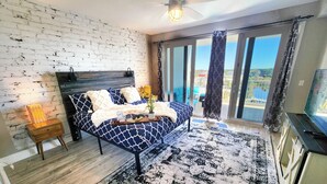 Een slaapkamer met een bed, een nachtkastje, een televisie en een balkon met uitzicht.