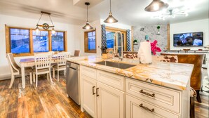 A modern kitchen with a marble countertop, white cabinetry, and pendant lighting.