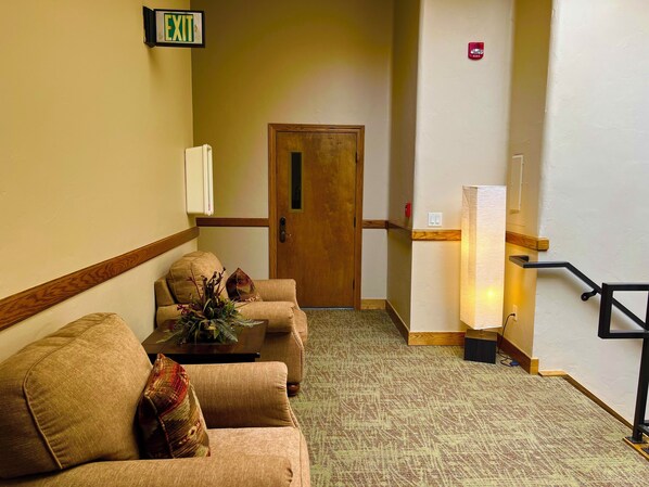 Un vestíbulo de hotel con un mostrador de recepción, una puerta de madera y una escalera con barandilla.