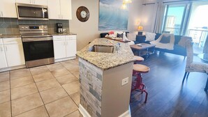 A modern kitchen with built-in appliances, a dining area with a view, and a living room with a large window. - Bring your Pet! Amazing 2nd floor unit! Outstanding Views and Amenities! (Panama City Beach)