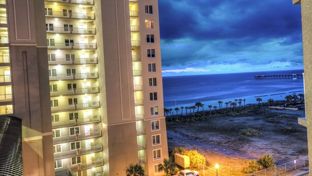 A high-rise building with multiple balconies, a beach view, and a pier in the distance. - Bring your Pet! Amazing 2nd floor unit! Outstanding Views and Amenities! (Panama City Beach)