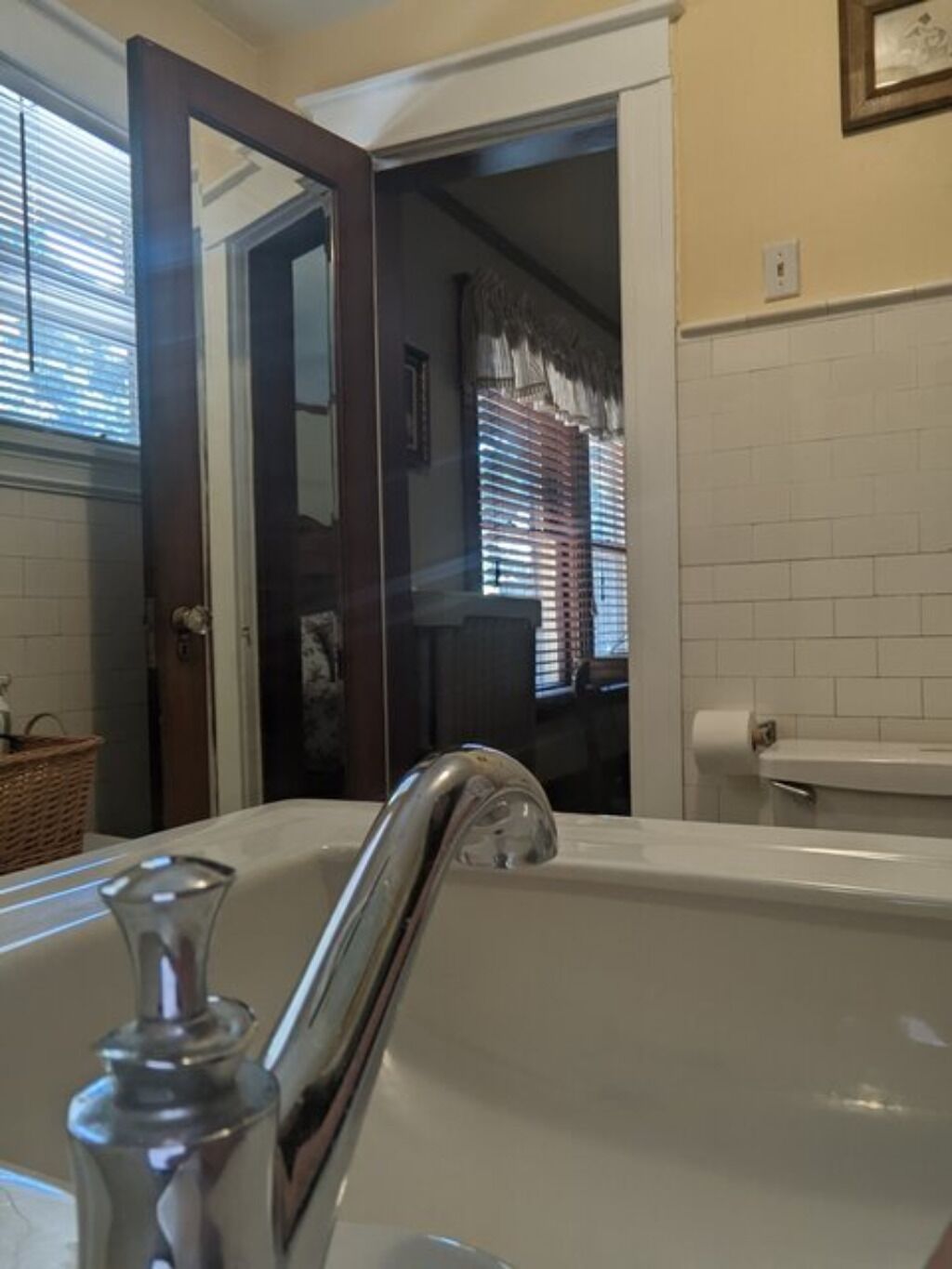 A bathroom with a white sink, a mirror, and a window with blinds.