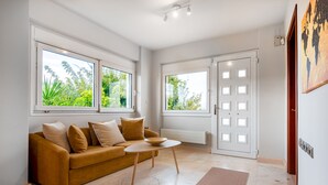 Una sala de estar moderna con un sofá, una mesa de centro y ventanas amplias.