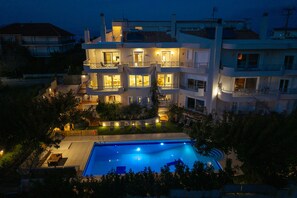 A multi-story residential building with a swimming pool, balconies, and outdoor lighting.