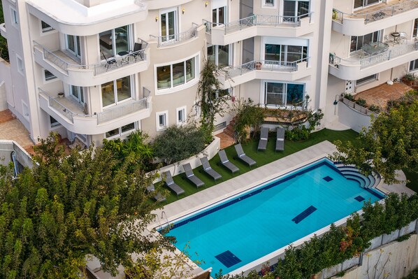 A multi-story building with balconies, a swimming pool, and a garden area.