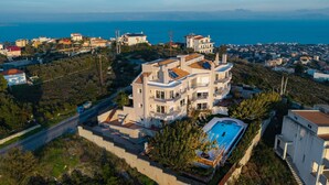 Un immeuble à plusieurs étages doté d’une piscine, entouré de verdure et offrant une vue sur la côte.