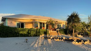 A modern house with a covered porch, a sandy driveway, and a stone fire pit. - New Private Pool, Private Beach and Flat, Private House, what else do you need? (Whymms)