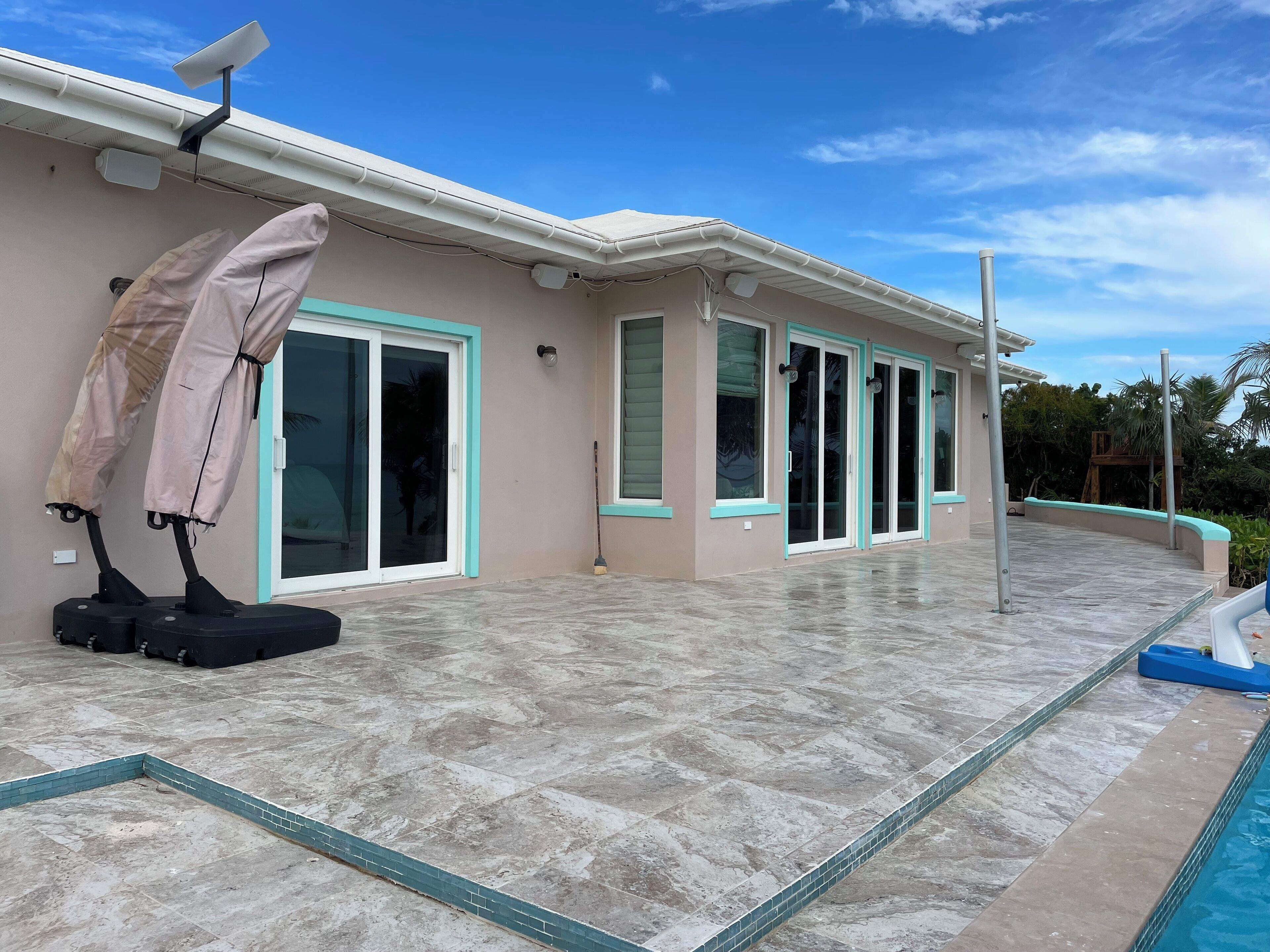 A modern house with a swimming pool, large glass doors, and a tiled patio.