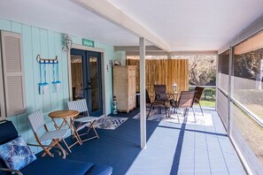 A covered outdoor area with blue walls, a wooden table, and two chairs.