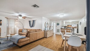 A modern living room with a brown leather sofa, a dining table set for four, and a kitchen in the background. - Manatee Cove Apartment Star5Vacations (Weeki Wachee)