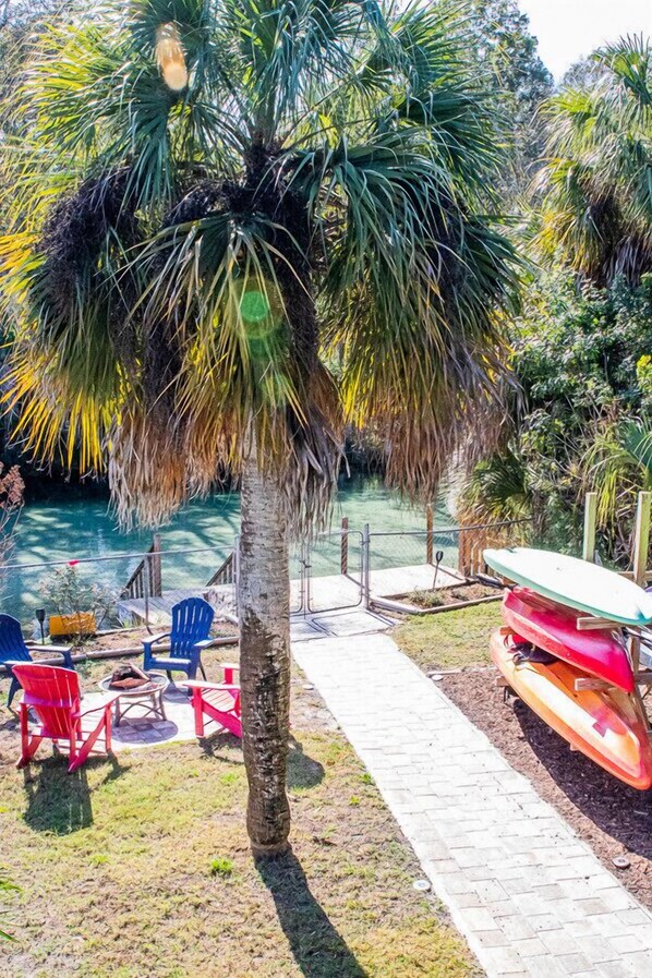 A pool area with a palm tree, red chairs, and a paddleboard.