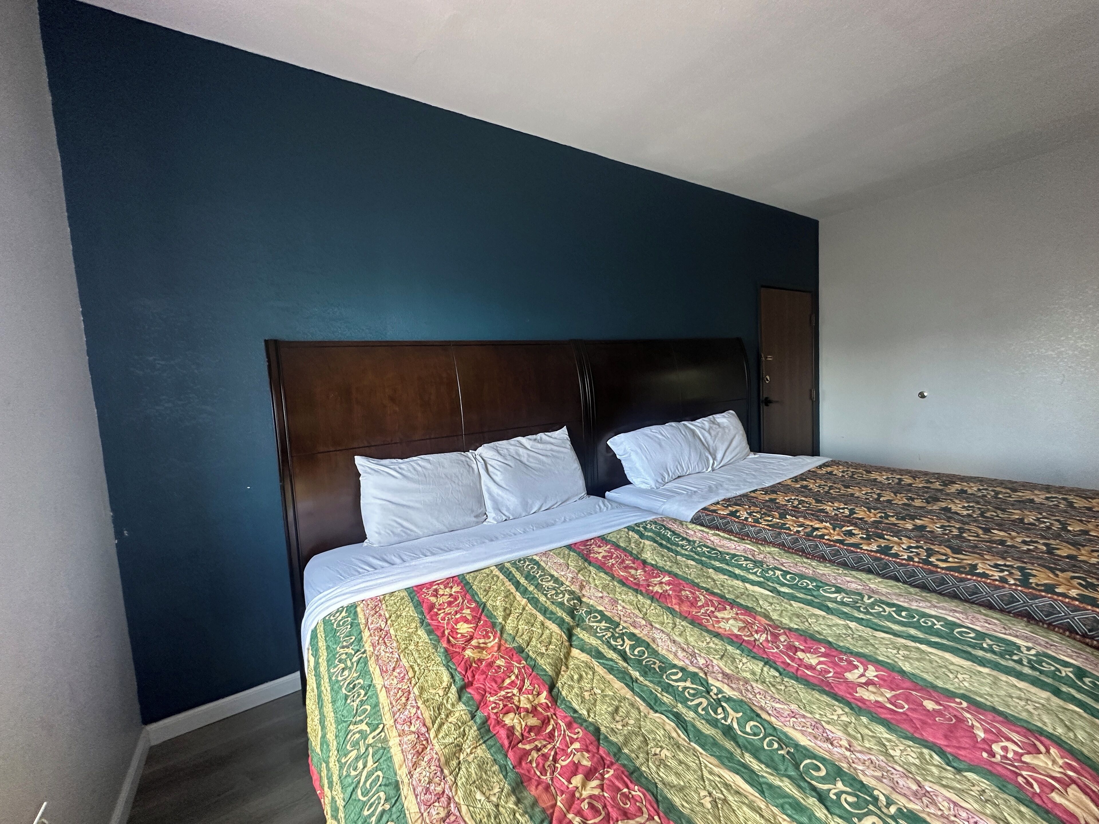 A bedroom with a large bed, dark headboard, and a patterned bedspread.