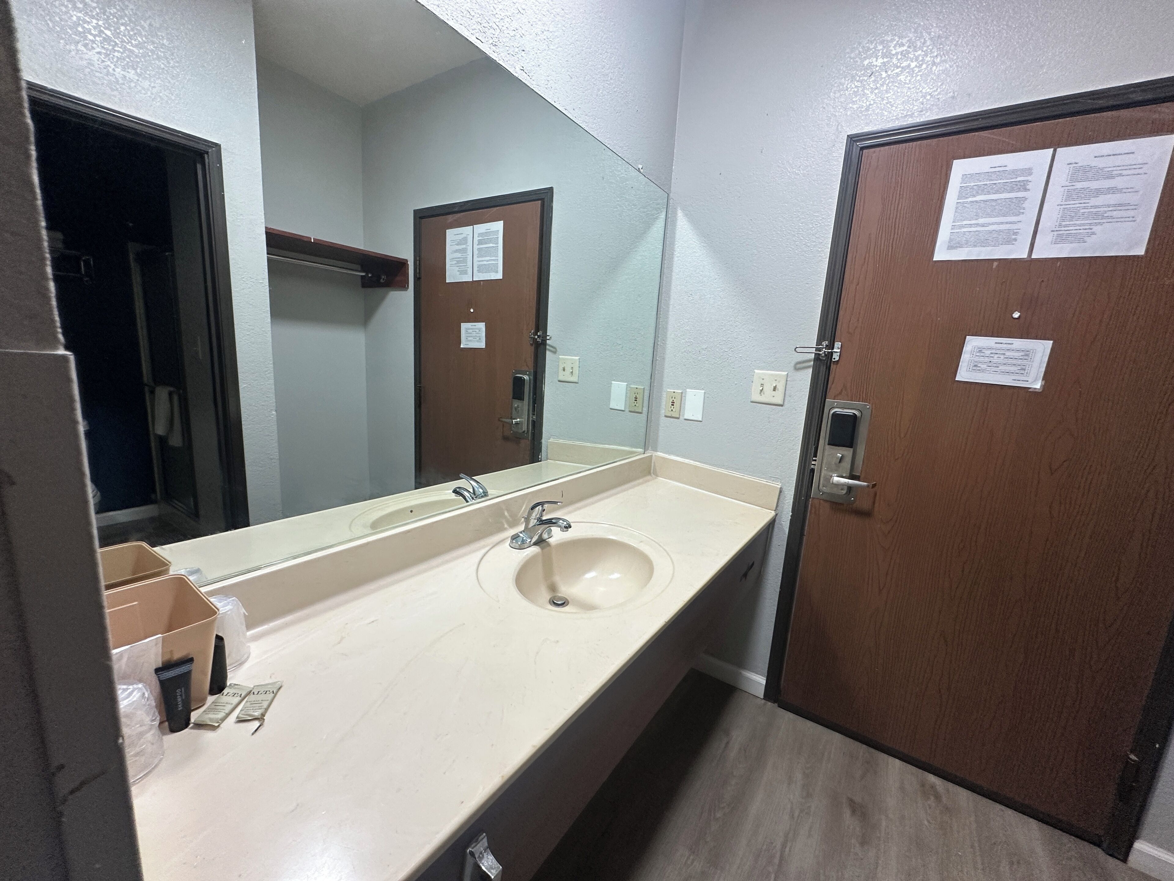 A bathroom with a sink, mirror, and wooden door.