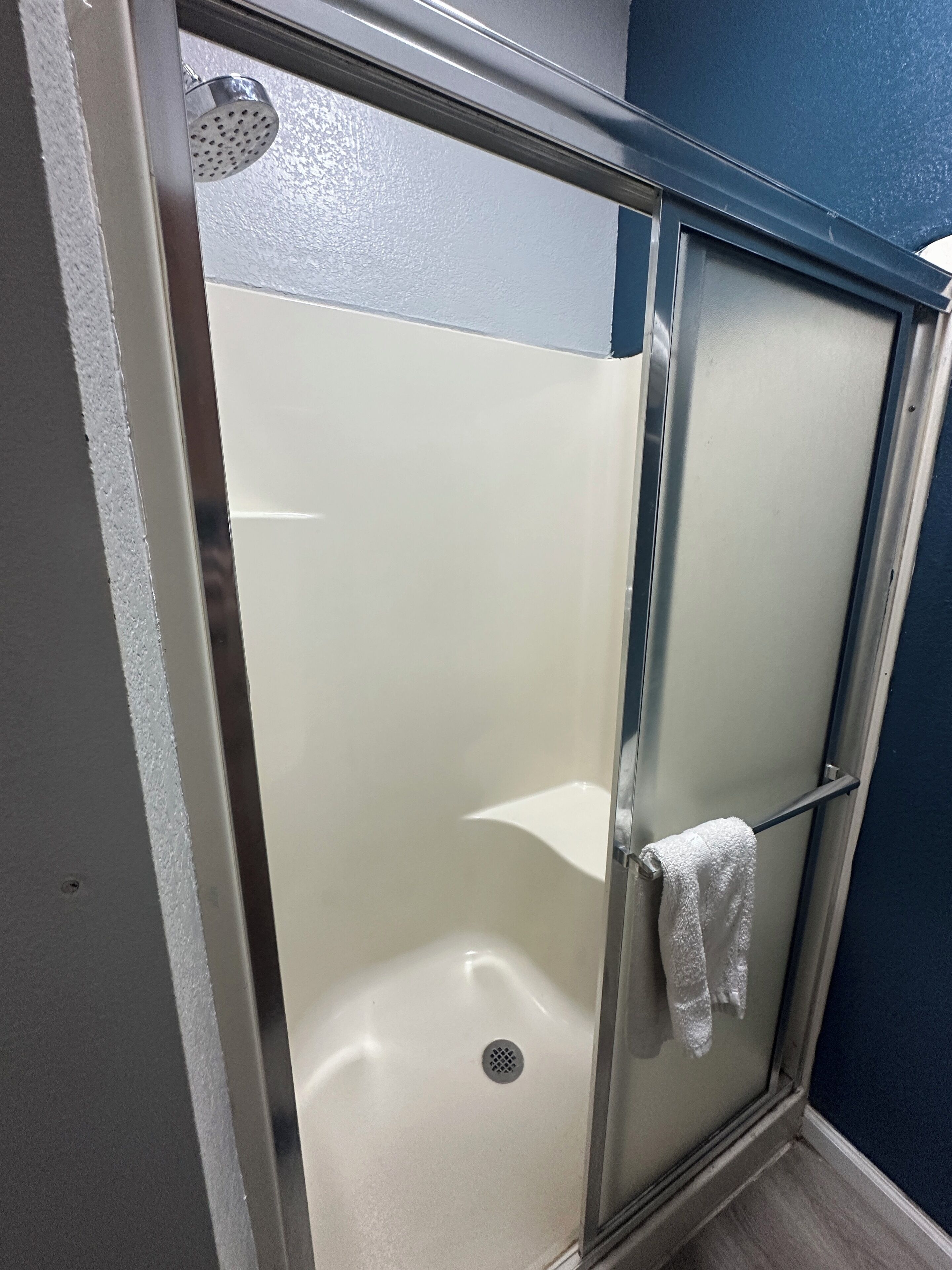 A glass-enclosed shower stall with a white towel hanging on the door handle.