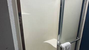 A glass-enclosed shower stall with a white towel hanging on the door handle.