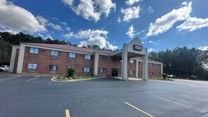 A Laramie Inn & Suites with a brick exterior, multiple windows, and a parking lot. - Budget Inn, Hwy 41 (Barnesville)