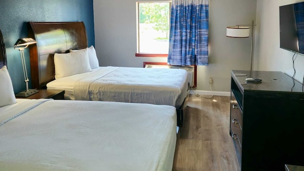 A hotel room with two beds, a desk, a television, and a window with curtains. - Budget Inn, Hwy 41 (Barnesville)