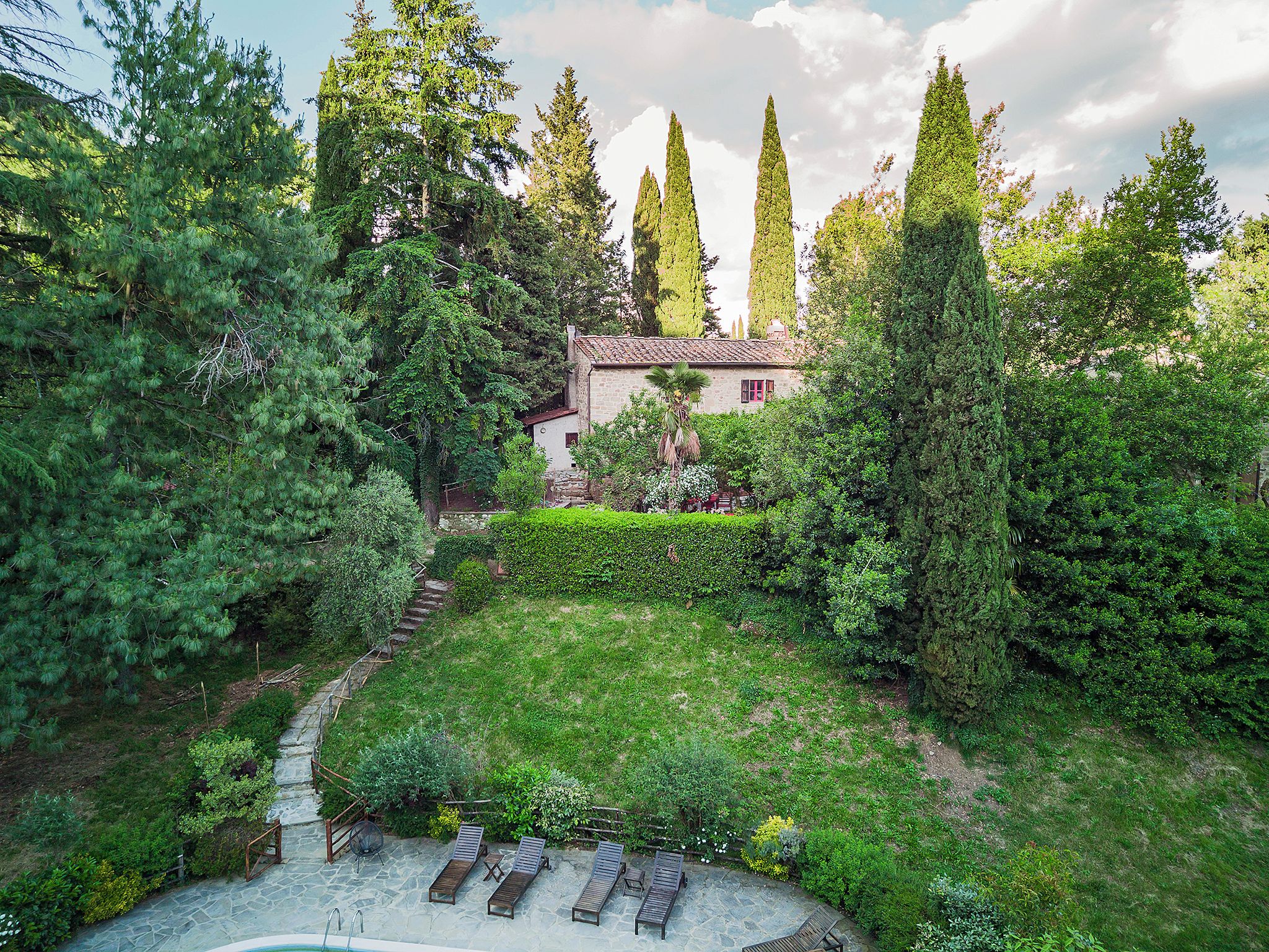 A stone pathway leading to a pool area with lounge chairs.