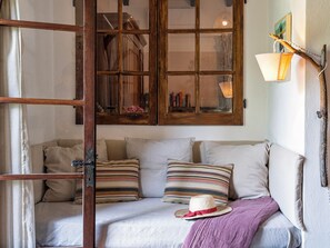 A cozy room with a wooden door, a cushioned bench, and a wall-mounted lamp. - Cozy little retreat in wonderful location, with pool (località Fornello, Pontassieve)