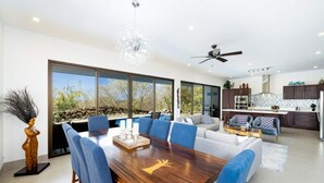 Un soggiorno moderno con zona pranzo, cucina e un'ampia finestra vista piscina.