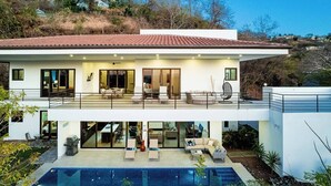 Una moderna casa a due piani con un ampio balcone, una piscina e un patio.