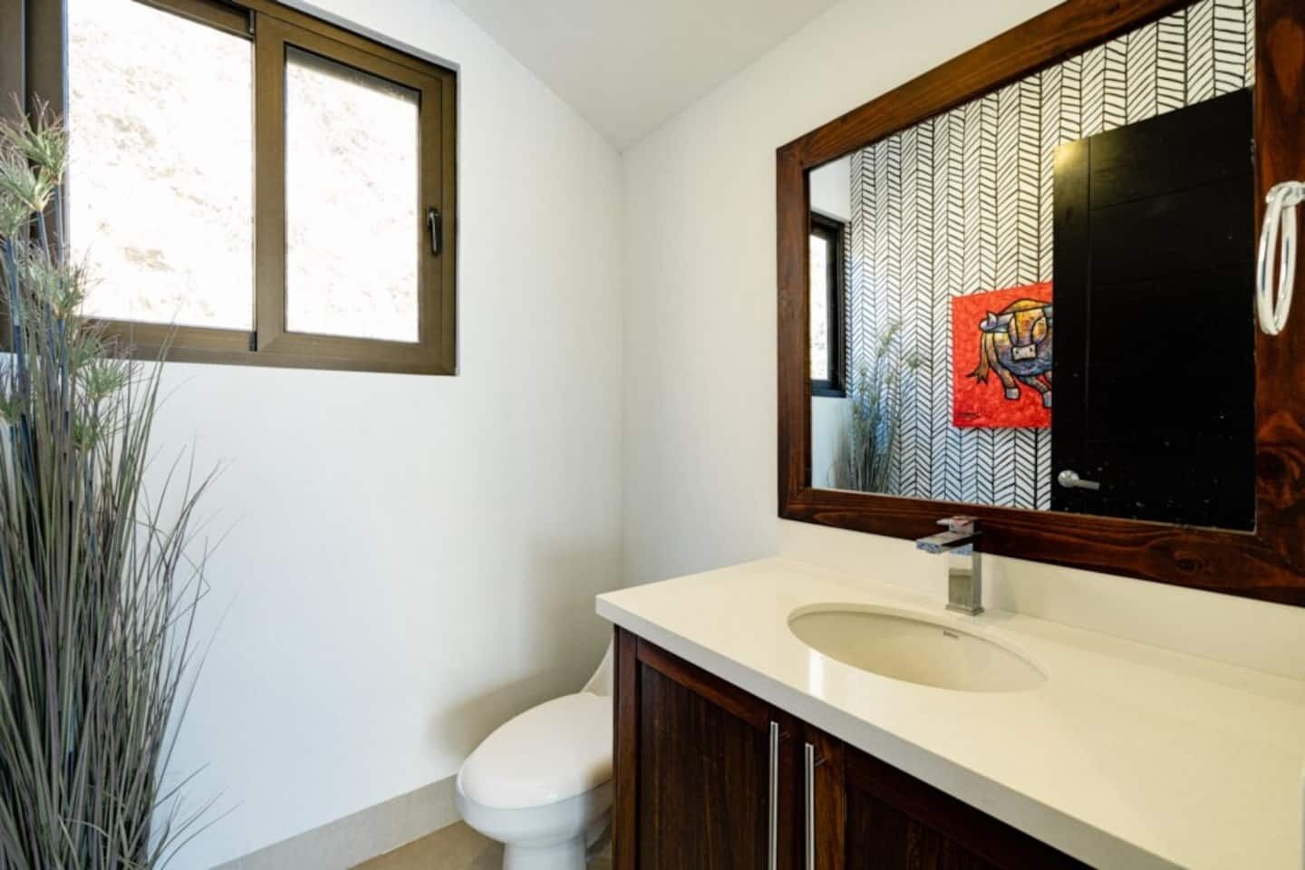 A bathroom with a white toilet, a beige sink, and a mirror with a chevron pattern.