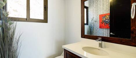 A bathroom with a white toilet, a beige sink, and a mirror with a chevron pattern.